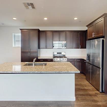 a kitchen with dark brown cabinets and a granite countertop.