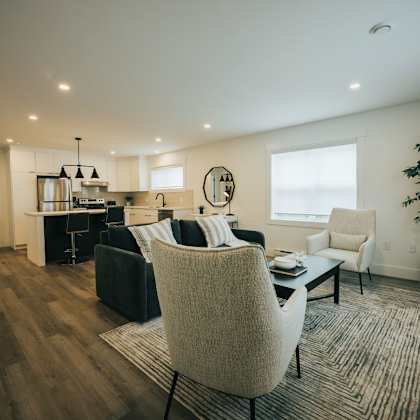 a modern living room with a black couch and a white chair.