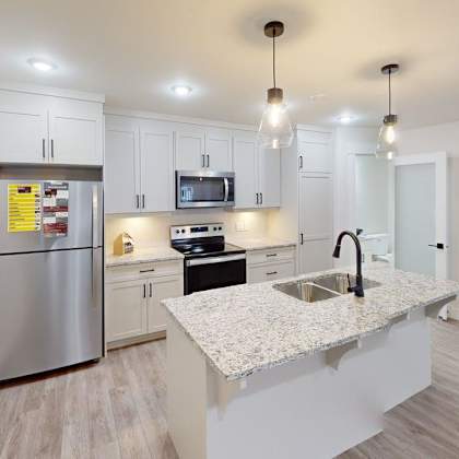 a modern kitchen with a stainless steel refrigerator, microwave, and sink.
