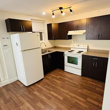 a kitchen with white appliances and wooden floors.