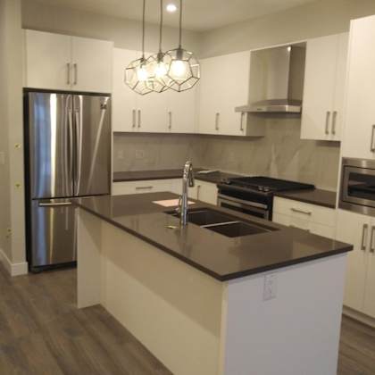 a modern kitchen with white cabinets and a dark countertop.