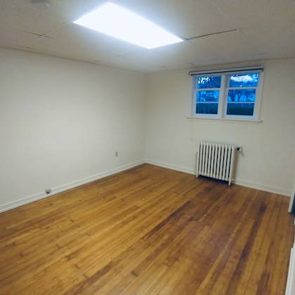 a room with wooden floors and a window with blinds.