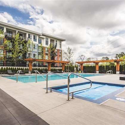 a large outdoor swimming pool with a diving board and a building in the background.