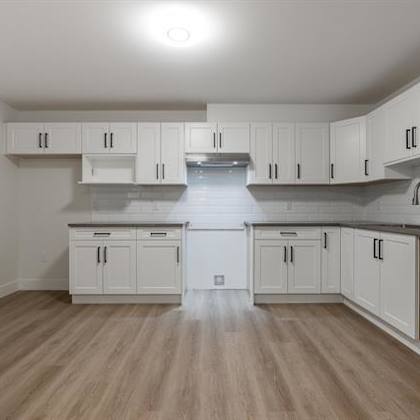 a kitchen with white cabinets and a wooden floor.