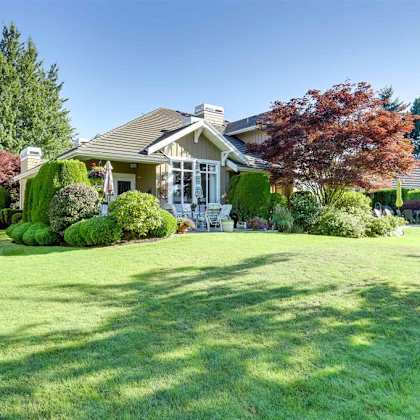 a house with a lawn and trees in front of it.