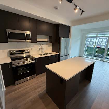 a modern kitchen with dark brown cabinets and a white island.