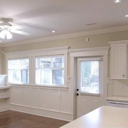 a large, empty room with a fireplace and a kitchen area.