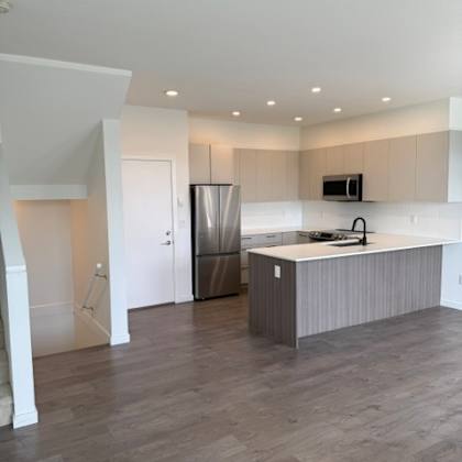 a kitchen with a refrigerator, sink, and cabinets.