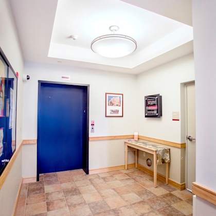 a hallway with a blue door and a bench.