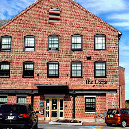 the lofts at stone pits is a red brick building with a parking lot in front.