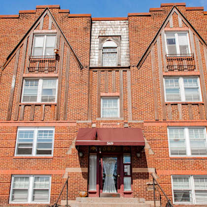 a red brick building with a balcony and a door.