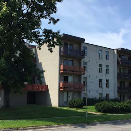 apartment building with balconies and greenery in front.