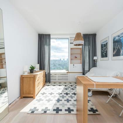 a well-lit, modern bedroom with a large window and a view of the city.