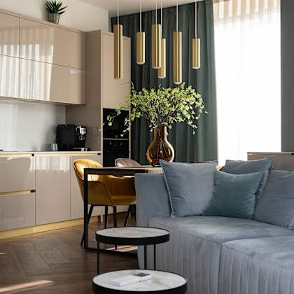 a modern living room with a sofa, a coffee table, and a kitchen area in the background.