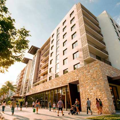 a modern building with a stone facade and large windows is surrounded by people walking on the sidewalk.