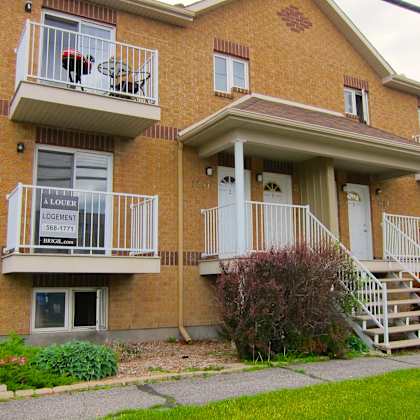a brick apartment building with a balcony and stairs leading to the front door.