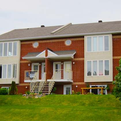 a red brick house with a white door and windows.