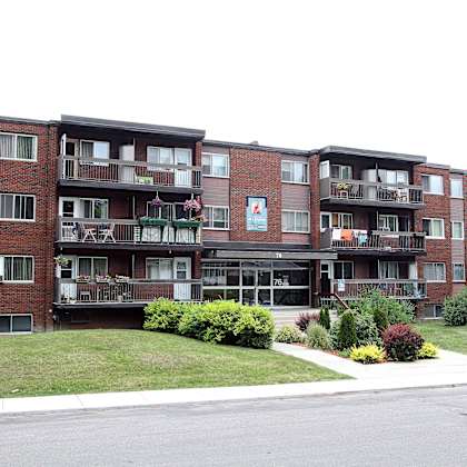 apartment building with a green bush in front.