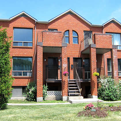 a red brick building with a balcony and stairs leading to the entrance.