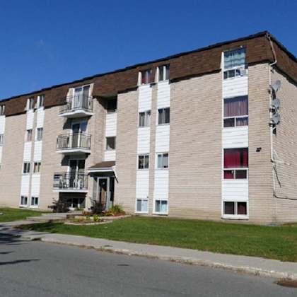 a large apartment building with a brown roof and white walls.