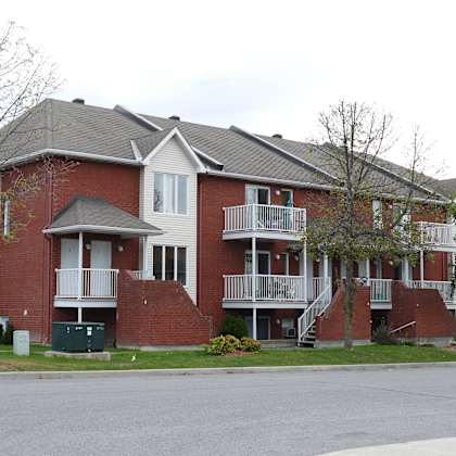 a red brick apartment building with a car parked in front.