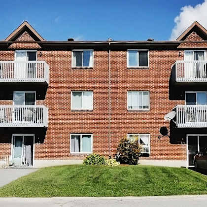 a red brick apartment building with a car parked in front.