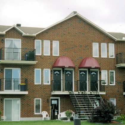 a red brick house with a balcony on the second floor.
