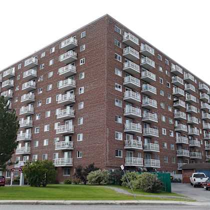 a large red brick apartment building with balconies on the upper floors.