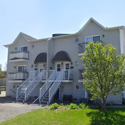 a large house with a balcony and a tree in front.
