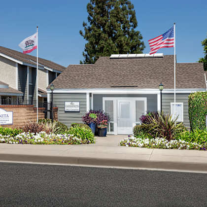 the leasing office with carmenita townhouse apartments signs surrounded by flowers and greenery out front.