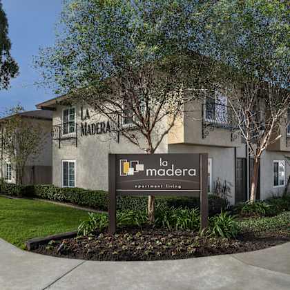 a sign for a community named la madera stands in front of a building.