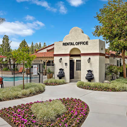 a rental office is surrounded by flowers and a pool.