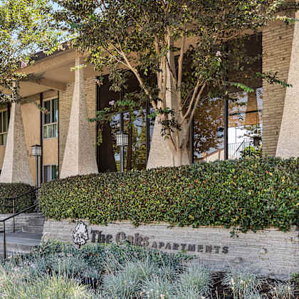 the oaks apartments building has a modern design with a beige exterior and large windows.