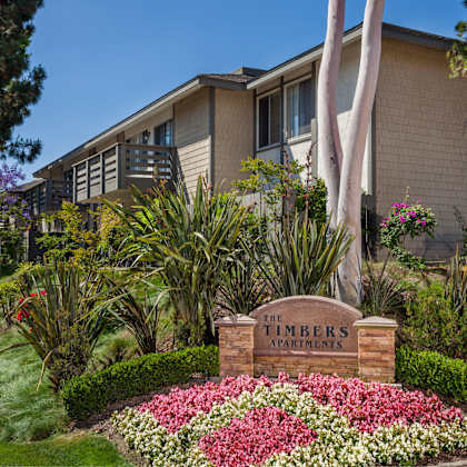 a sign that says "the timbers apartments" is in front of a building.