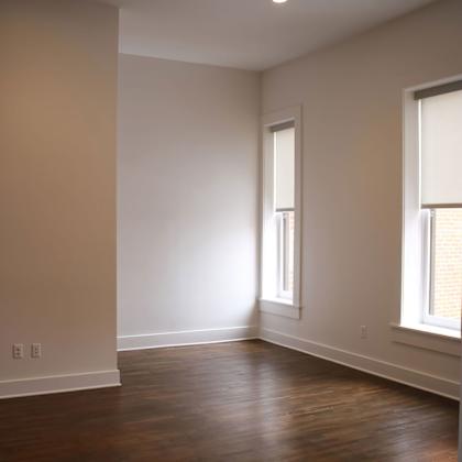 a room with wooden floors and two windows.