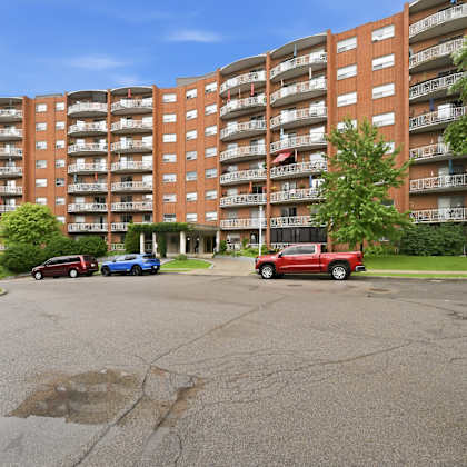 a red truck is parked in a parking lot in front of a large apartment building.