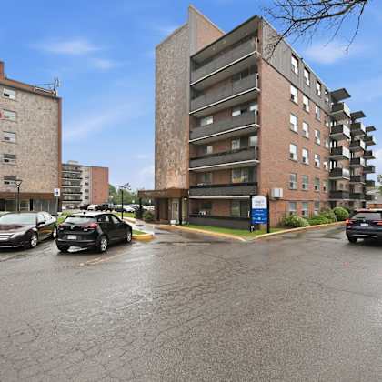 a parking lot with cars and two buildings in the background.