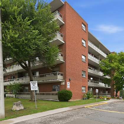 a red brick apartment building with a parking lot in front.
