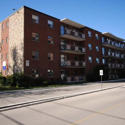 a large red brick apartment building with a white sign on the right side.