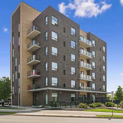 a modern apartment building with balconies and a black fence in front.