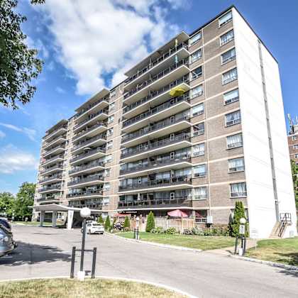 a tall residential building with a parking lot in front.
