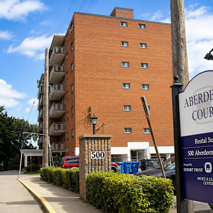 a sign for aberdeen court rental suites stands in front of a brick building.