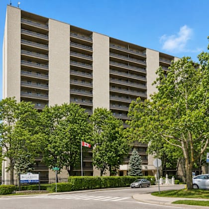 a large building with a lot of windows and trees in front.