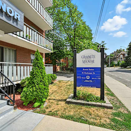 a sign for granite manor apartments stands in front of a building entrance.