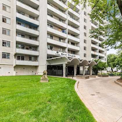 a large white apartment building with a green lawn in front.