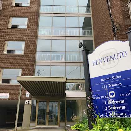 a sign for benvenuto rental suites stands in front of a building.