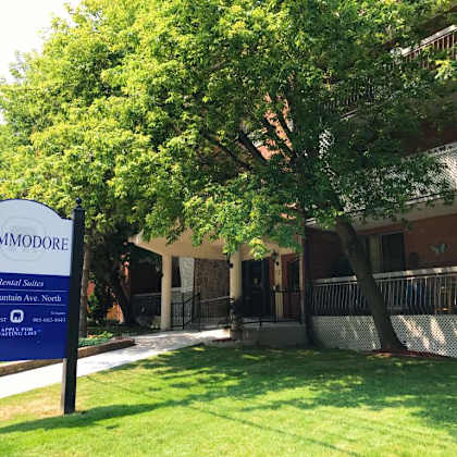 a sign for commodore apartment homes stands in front of a building.