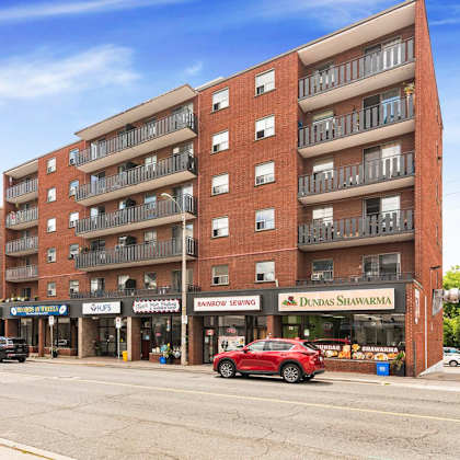 a red car is parked in front of a building with a sign that says "dundas shawarma.".