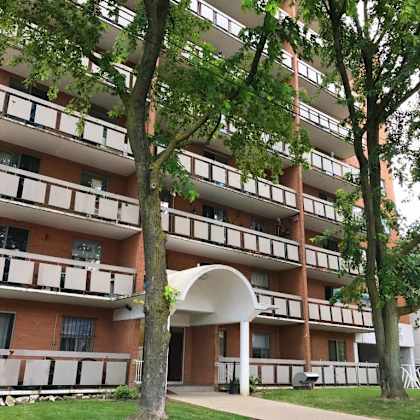 a tall apartment building with balconies and a blue sign in front.