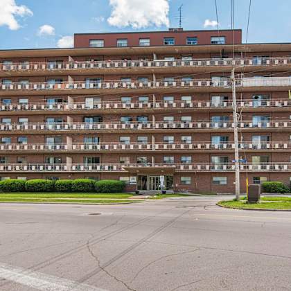 a large apartment building with a parking lot in front.